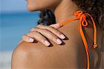 Woman touching bare shoulder at the beach, cropped