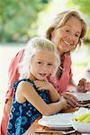 Girl having meal with grandmother outdoors