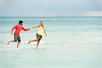 Couple running hand in hand in surf at the beach