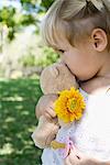 Petite fille en tenue d'ours en peluche, fleurs et suce