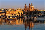 Port Luzzu bateaux de pêche et église paroissiale Marsaxlokk au lever du soleil, Marsaxlokk, Malte, la Méditerranée, l'Europe