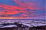 Feurige Sonnenuntergang über einem Schnee bedeckt Gormire See von Sutton Bank am Rande der North Yorkshire Moors, Yorkshire, England, Vereinigtes Königreich, Europa