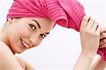 Portrait d'une jeune femme regardant la caméra, serviette de toilette rose sur sa tête