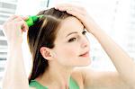 Portrait of a young woman pouring on hair lotion on her head