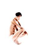 Femme nue en culotte, accroupi, la main sur son cou (studio)