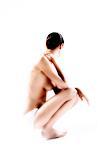 Naked woman in panties, crouching, hand on her neck (studio)