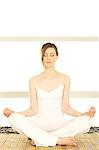 Young woman sitting cross-legged, yoga attitude, shut eyes