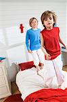 2 boys standing on bed