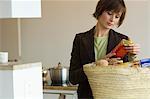 Young woman emptying shopping basket in the kitchen