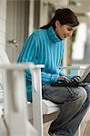 Jeune femme assise sur une chaise, en utilisant un ordinateur portable, à l'extérieur