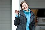 Young woman holding car keys outdoors, smiling for the camera