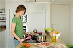 Young woman cooking, looking at the camera