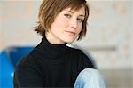 Young woman sitting on the floor, looking at the camera