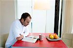 Man sitting in the kitchen, reading a magazine