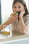 Portrait of a little girl eating an apple, looking at the camera