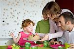 Couple and 2 little girls with birthday cake at lunch table