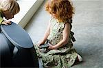 Little girl kneeling in front of television, holding remote control, elevated view