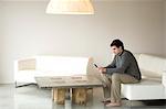 Man sitting on a sofa in living-room, using mobile phone