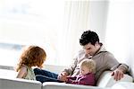 Mann mit 2 Kindern im Wohnzimmer sitzen