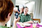 Boy taking picture of senior couple with camera phone