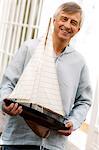 Smiling senior man holding a model boat outdoors