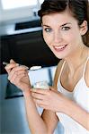 Young woman eating a plain yogurt