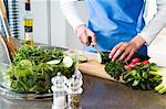 Woman making a salad, chopping cucumber, close-up