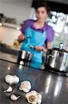 Woman cooking, garlic at the foreground