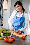 Jeune femme souriante, faire une salade, hacher les tomates