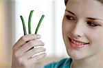 Woman holding 3 string beans, close-up