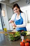 Young smiling woman seasoning a salad