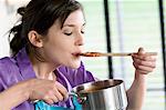 Young woman tasting tomato sauce