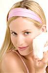 Portrait of a young woman with powder puff on her cheek, indoors (studio)