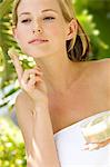 Young woman applying face scrub cream on her face, outdoors