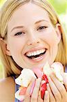 Portrait of a young  blond woman smiling, holding petals, outdoors