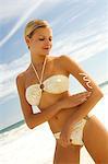 Junge Frau im Bikini am Strand Sun Creme anwenden