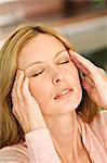 Woman with hands on temples, eyes closed