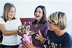 Teenage boy ang girl offering gifts to smiling woman