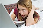 Junges Mädchen liegend auf dem Bett, mit laptop
