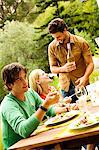 2 men and a woman sitting at garden table