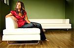 Femme jeune pensée assise sur un canapé