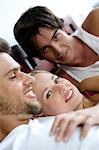 2 smiling men and a woman lying in bed