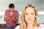 Portrait of a young thoughtful woman, man in background, indoors