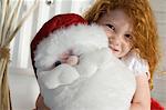 Jour de Noël, portrait d'une petite fille tenant une peluche (Santa Claus), à l'intérieur
