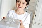 Portrait of a little boy offering a Christmas present, indoors