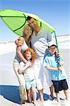 Parents and two children on the beach, posing for the camera, outdoors