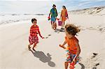 Parents and two children walking on the beach, outdoors