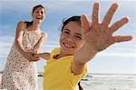 Mother and daughter on the beach, girl stretching out her hand, outdoors