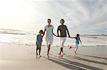 Couple, son and daughter walking on the beach, outdoors