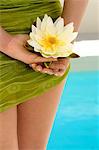 Young woman holding a water lily, pool, outdoors